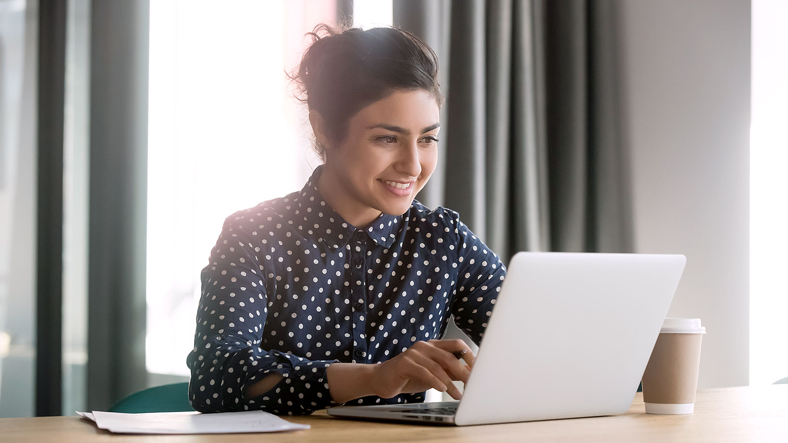 Une consultante souriante travaille sur son ordinateur portable